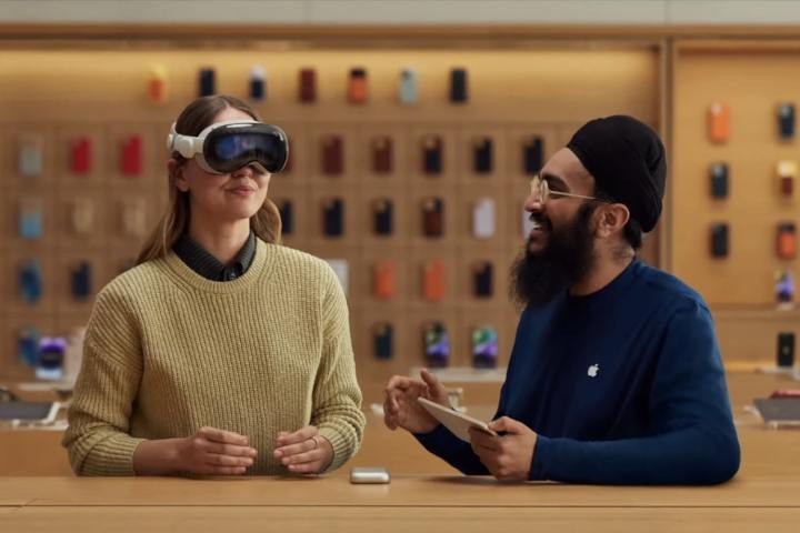 Un employé d'Apple montre une personne comment utiliser un casque Vision Pro dans un magasin Apple.