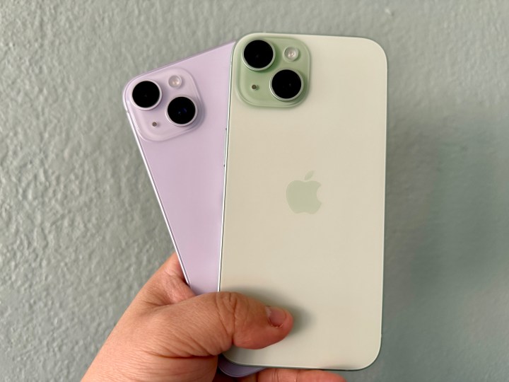 IPhone 14 violet (à gauche) et un iPhone 15 vert à la main.