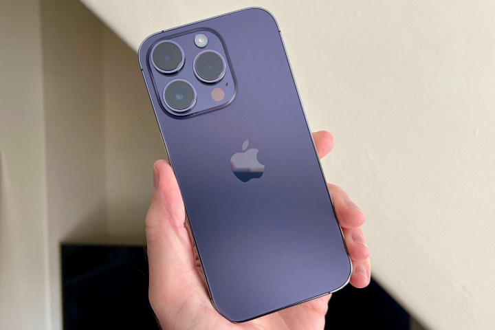 iPhone 14 Pro à Deep Purple, tenu dans une main de l'homme.