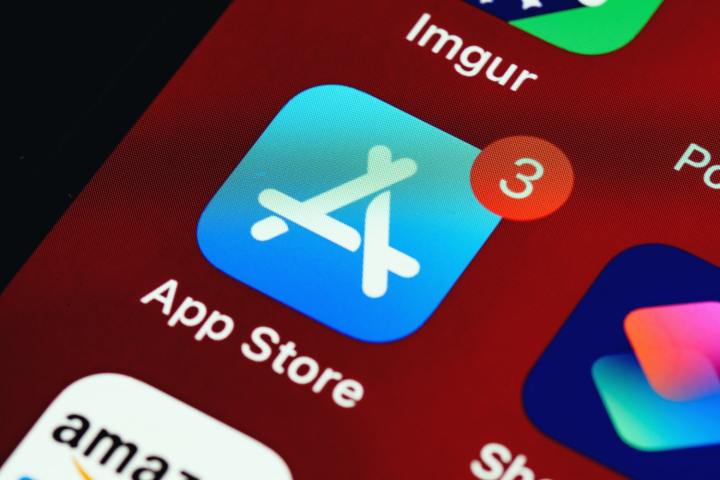Une photo d'un écran Apple et un gros plan de l'icône de l'App Store avec trois notifications dessus.