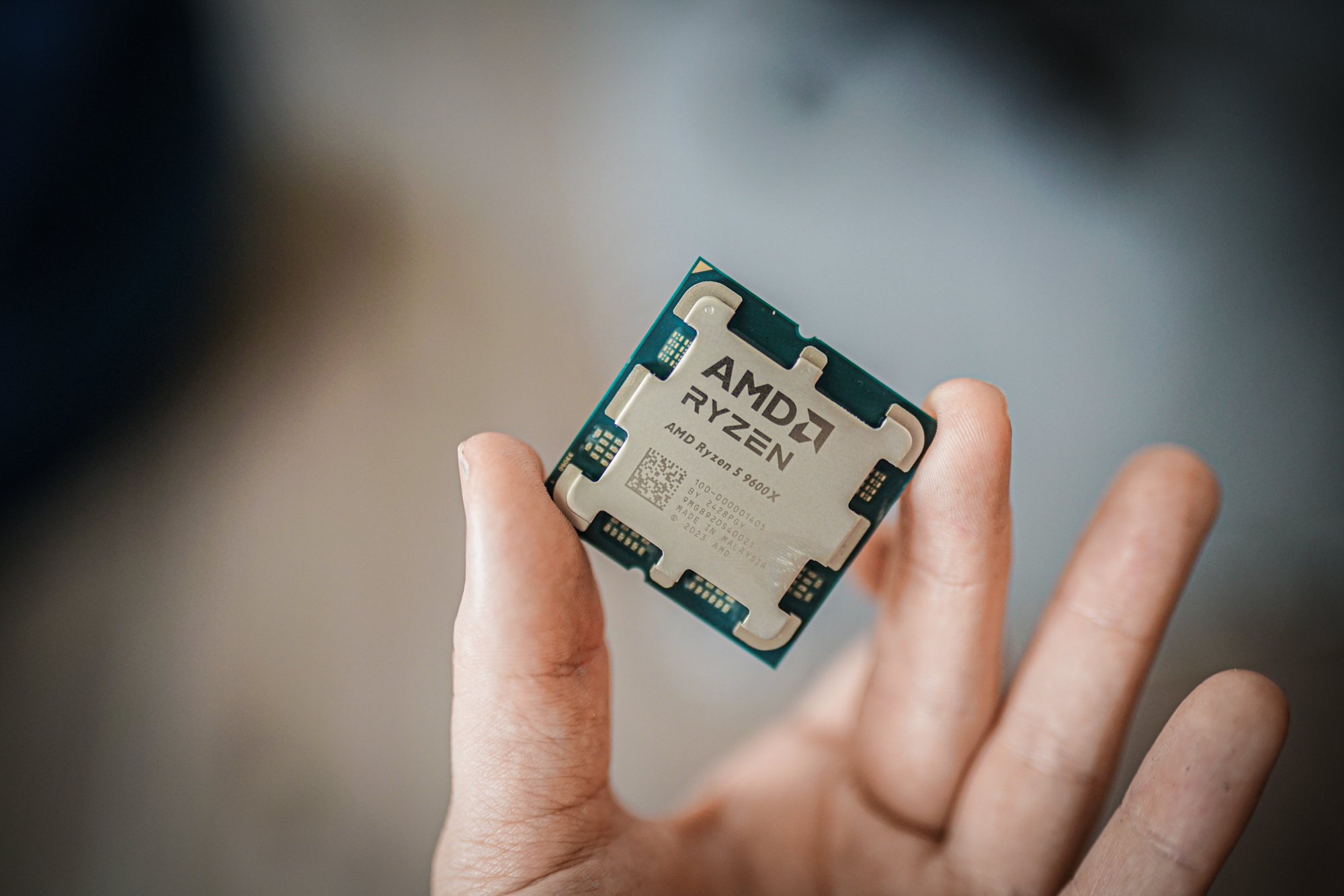 L'AMD Ryzen 5 9600X entre deux pointes de doigts.