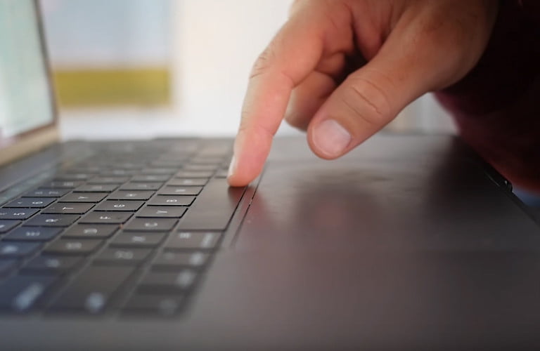 Vue latérale Apple MacBook Pro montrant le doigt sur le clavier.