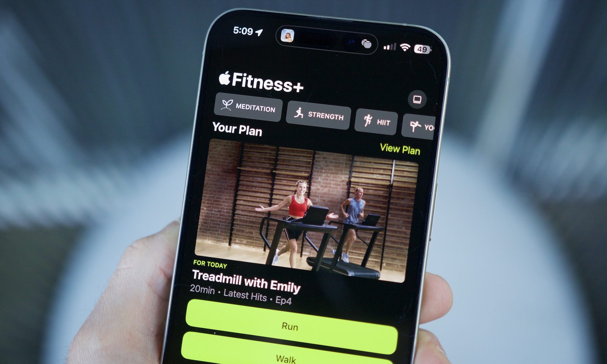 Quelqu'un tenant un iPhone avec l'application Apple Fitness ouverte, montrant la fonctionnalité des plans personnalisés.