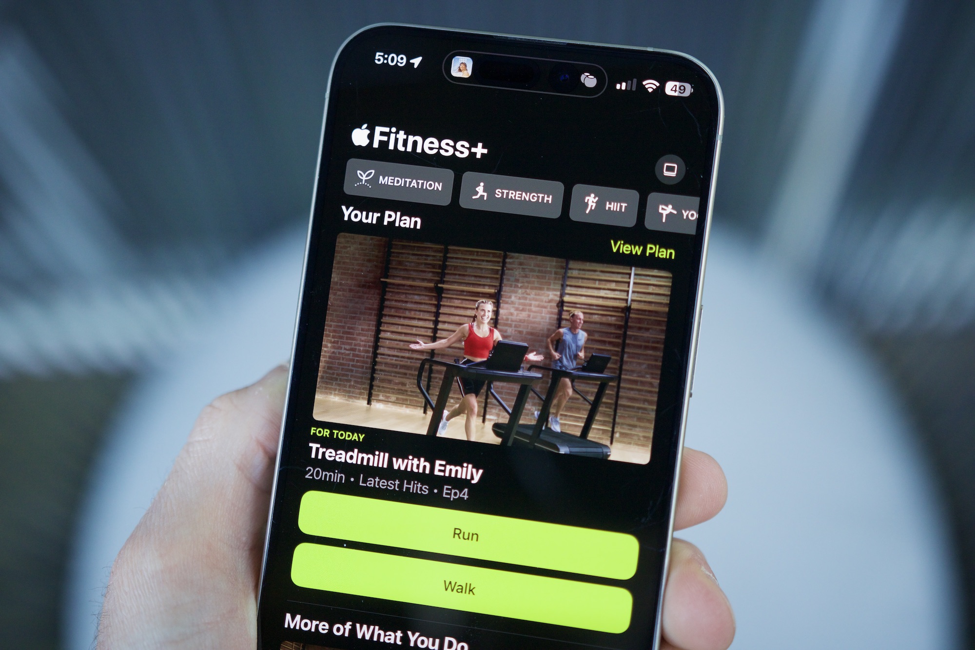Quelqu'un tenant un iPhone avec l'application Apple Fitness ouverte, montrant la fonctionnalité des plans personnalisés.