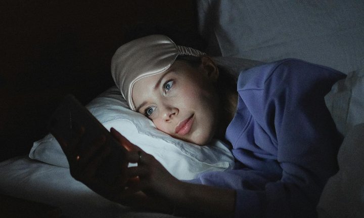 Personne utilisant un téléphone sur le lit.