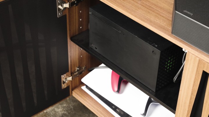 Xbox Series X et une PS5 sur les étagères d'une armoire multimédia.
