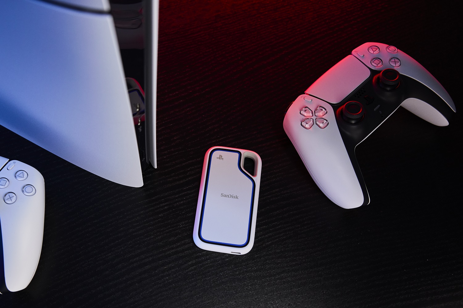 Le SSD portable SanDisk Extreme pour PlayStation 5 et PC, avec la PS5 et les manettes.