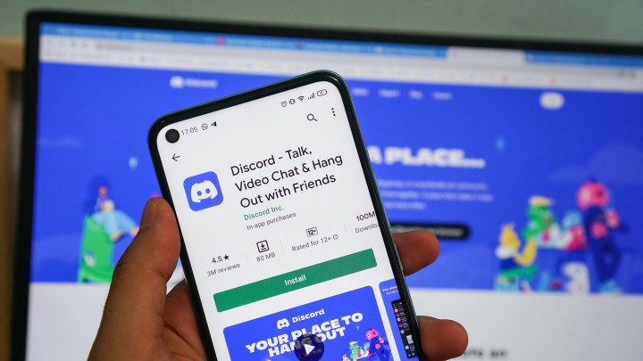 Une personne tenant un smartphone avec l’application Discord affichée.