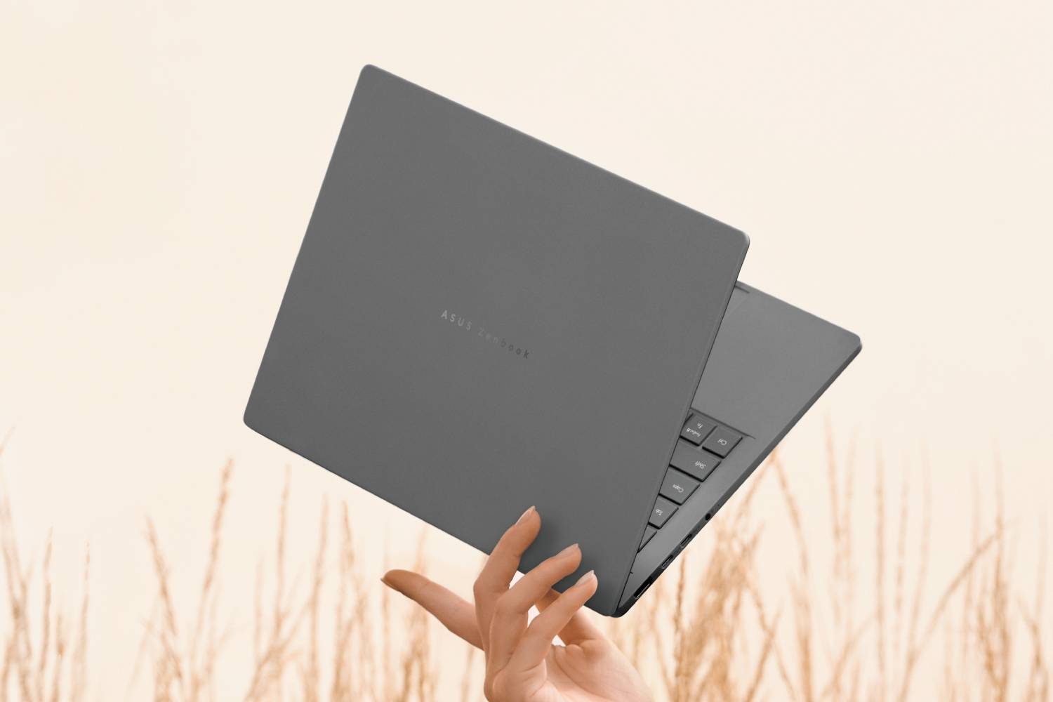 Une main tenant le Zenbook A14 entre ses doigts.