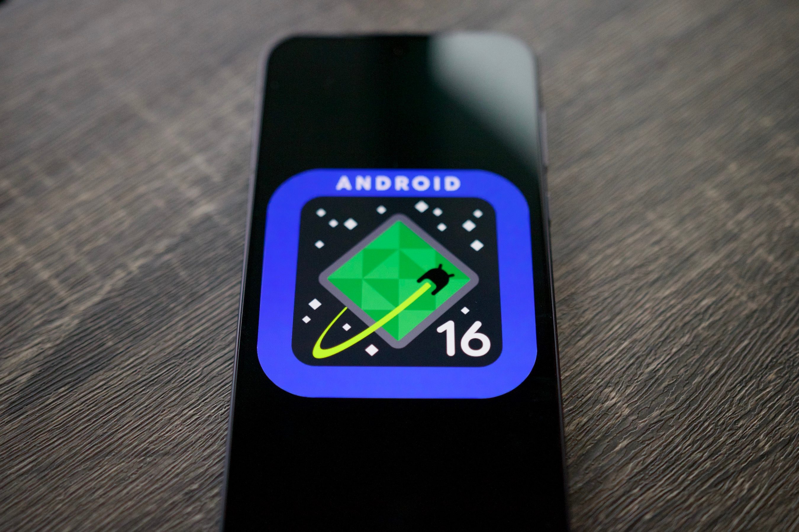 Le logo Android 16 sur un smartphone, posé sur une étagère.