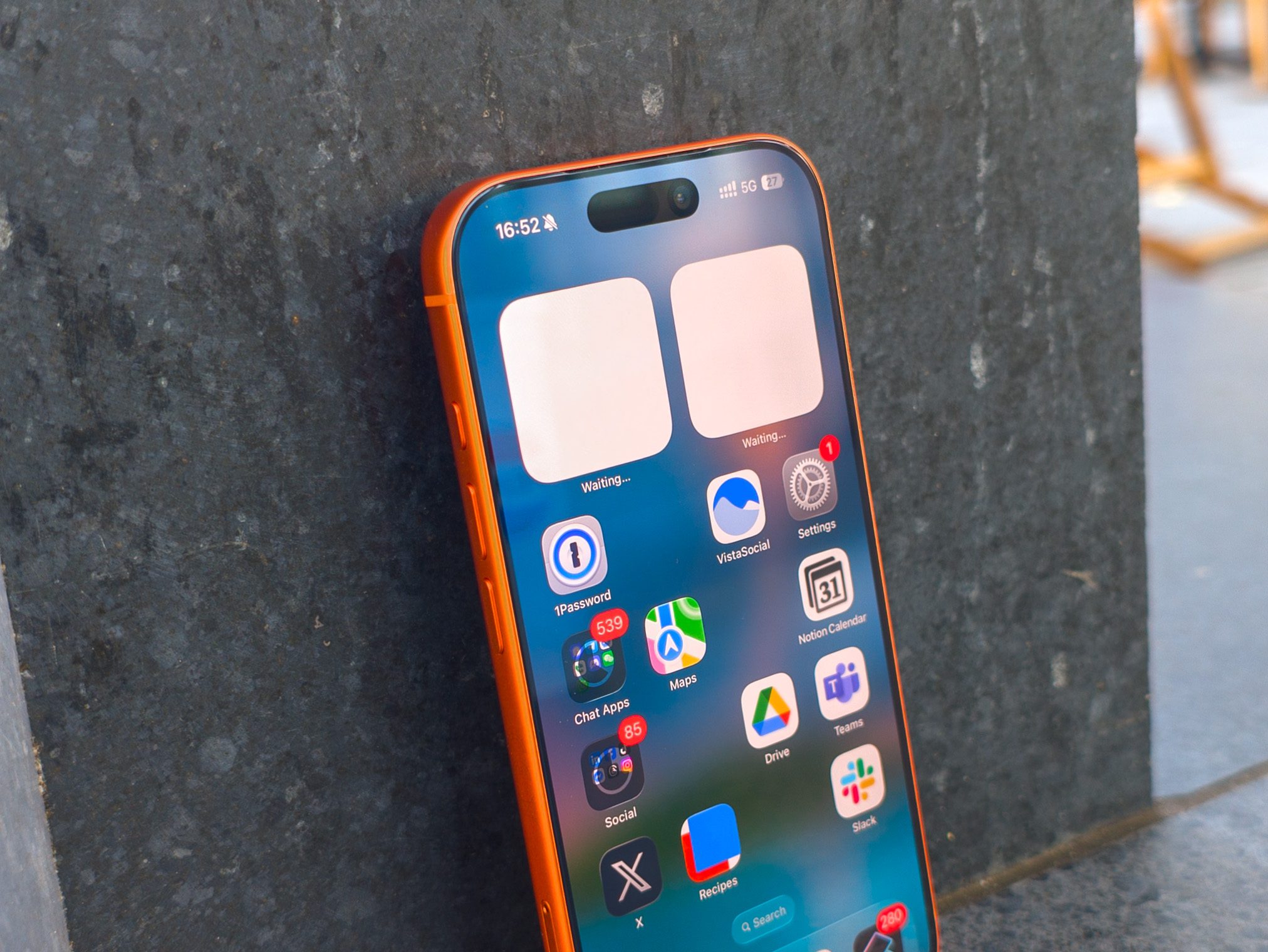 Apple iPhone 17 Pro en Cosmic Orange appuyé sur un mur gris.