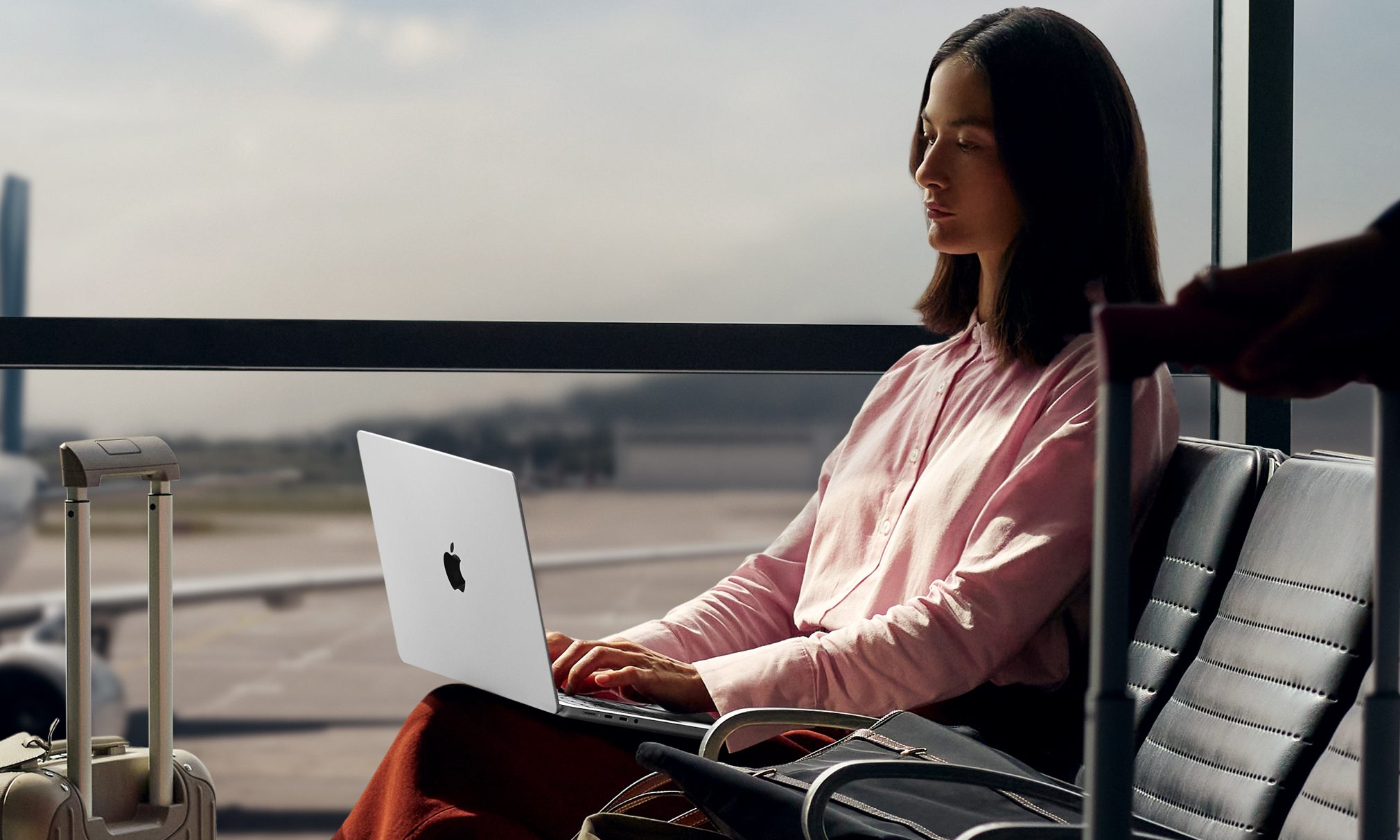 L'Apple MacBook Pro 14 M5 posé sur les genoux d'une femme à l'aéroport.