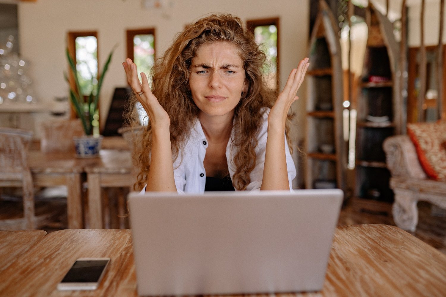 Une personne qui a l'air frustrée devant un ordinateur portable alors qu'elle est assise à une table.