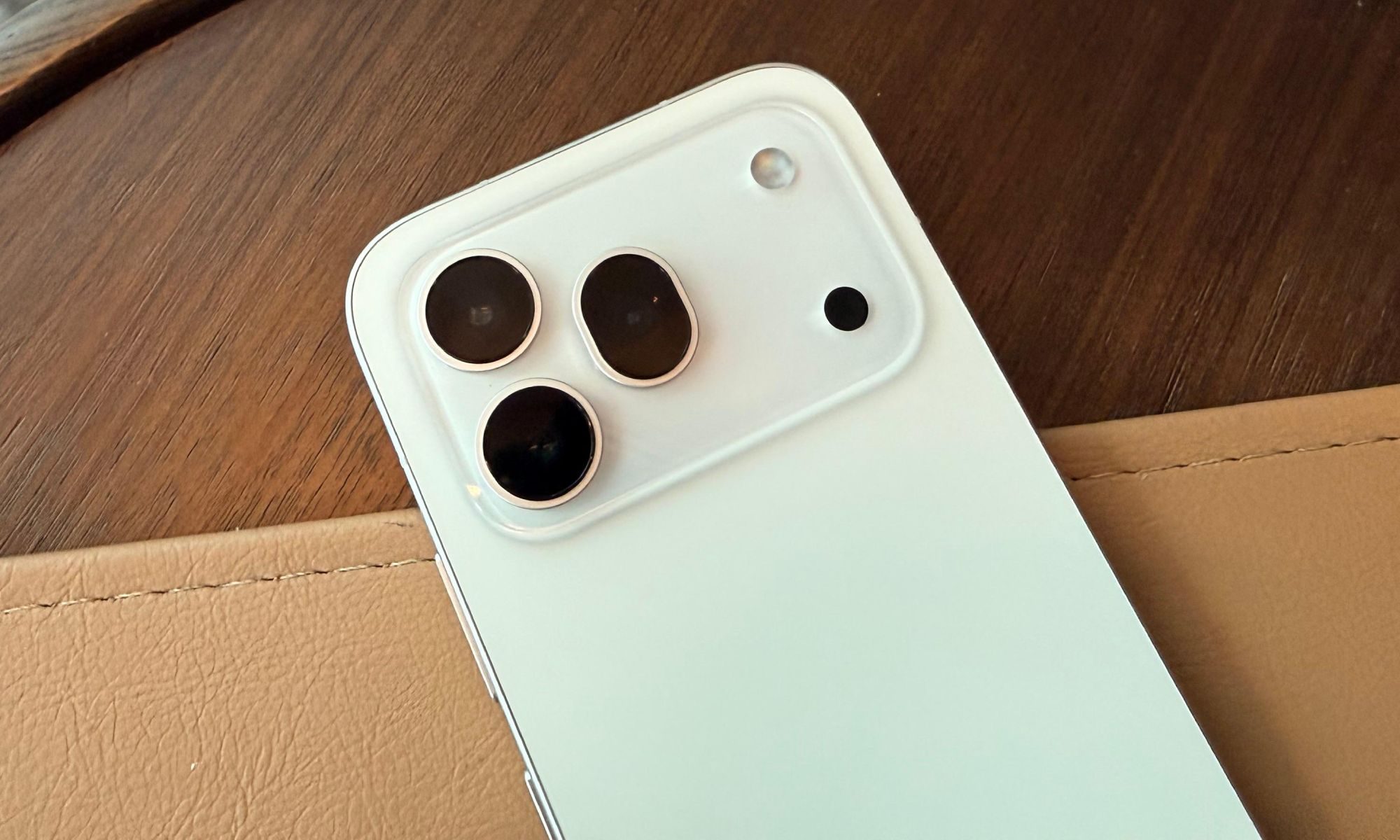 Honor 600 Pro blanc posé sur un tapis en cuir sur une table en bois.