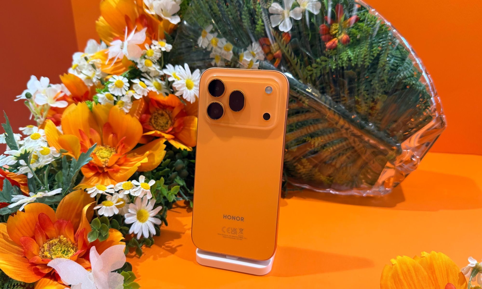 Orange Honor 600 Pro affiché sur une table entourée de fleurs.
