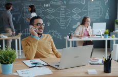 Man talking on phone in modern office with team