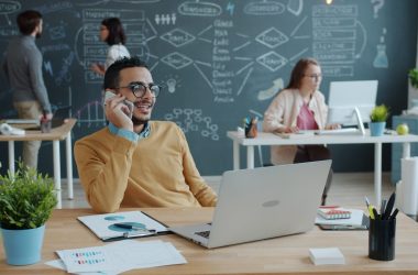 Man talking on phone in modern office with team