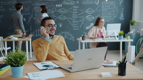 Man talking on phone in modern office with team
