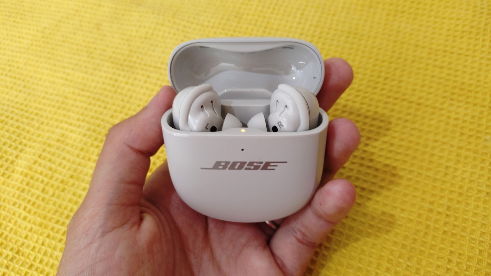 Bose QC Ultra 2e génération dans leur étui, détenu sur fond jaune