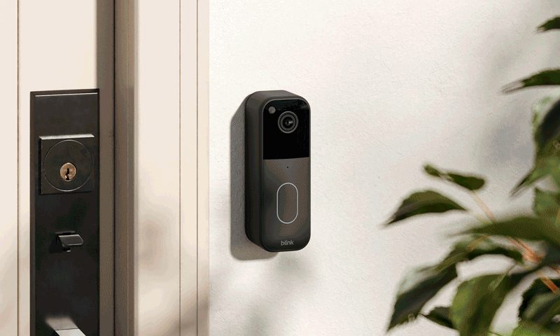Le modèle 2023 de la sonnette vidéo Blink sur un mur à côté d'une porte d'entrée