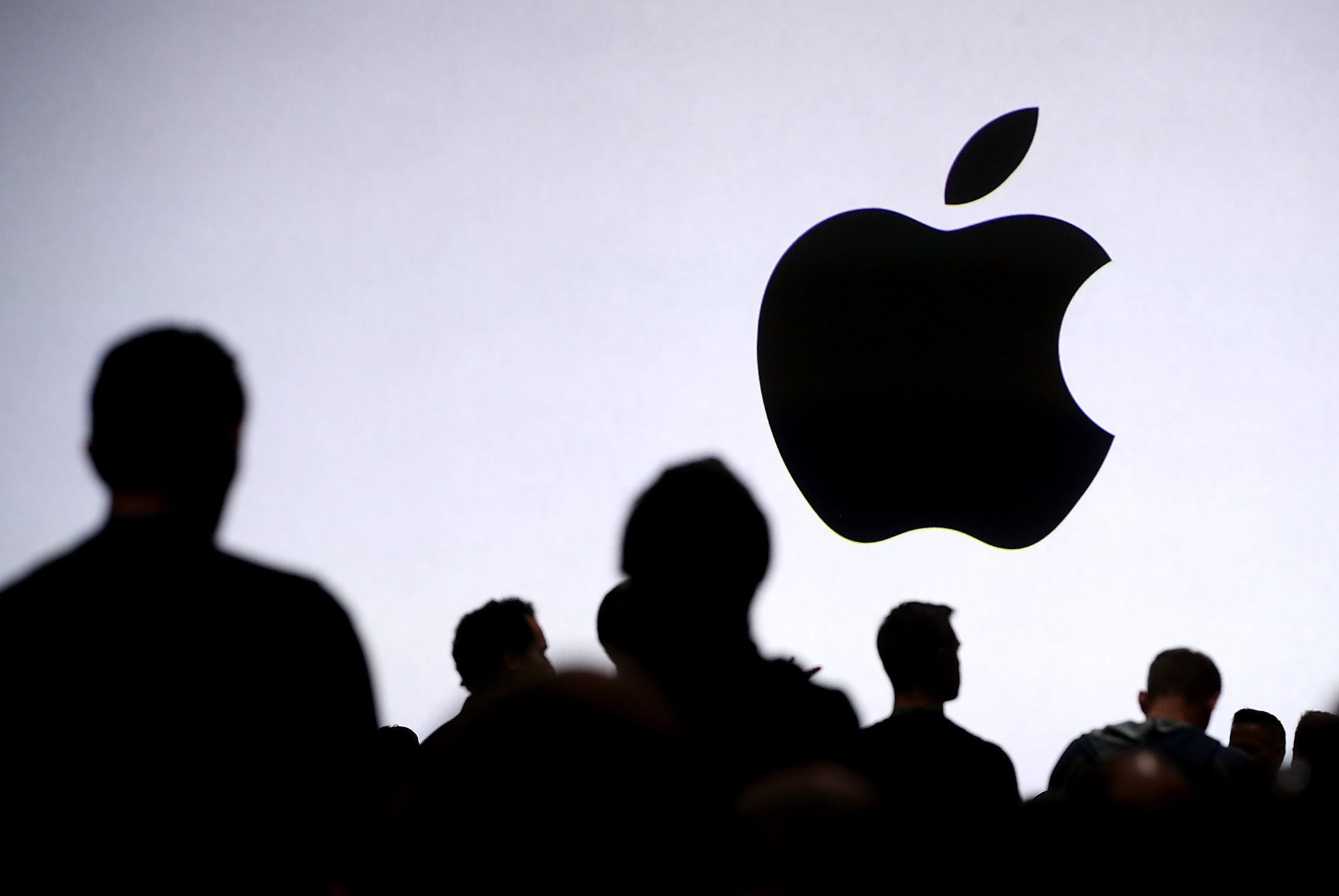 Logo Apple à l'écran devant un groupe de personnes.