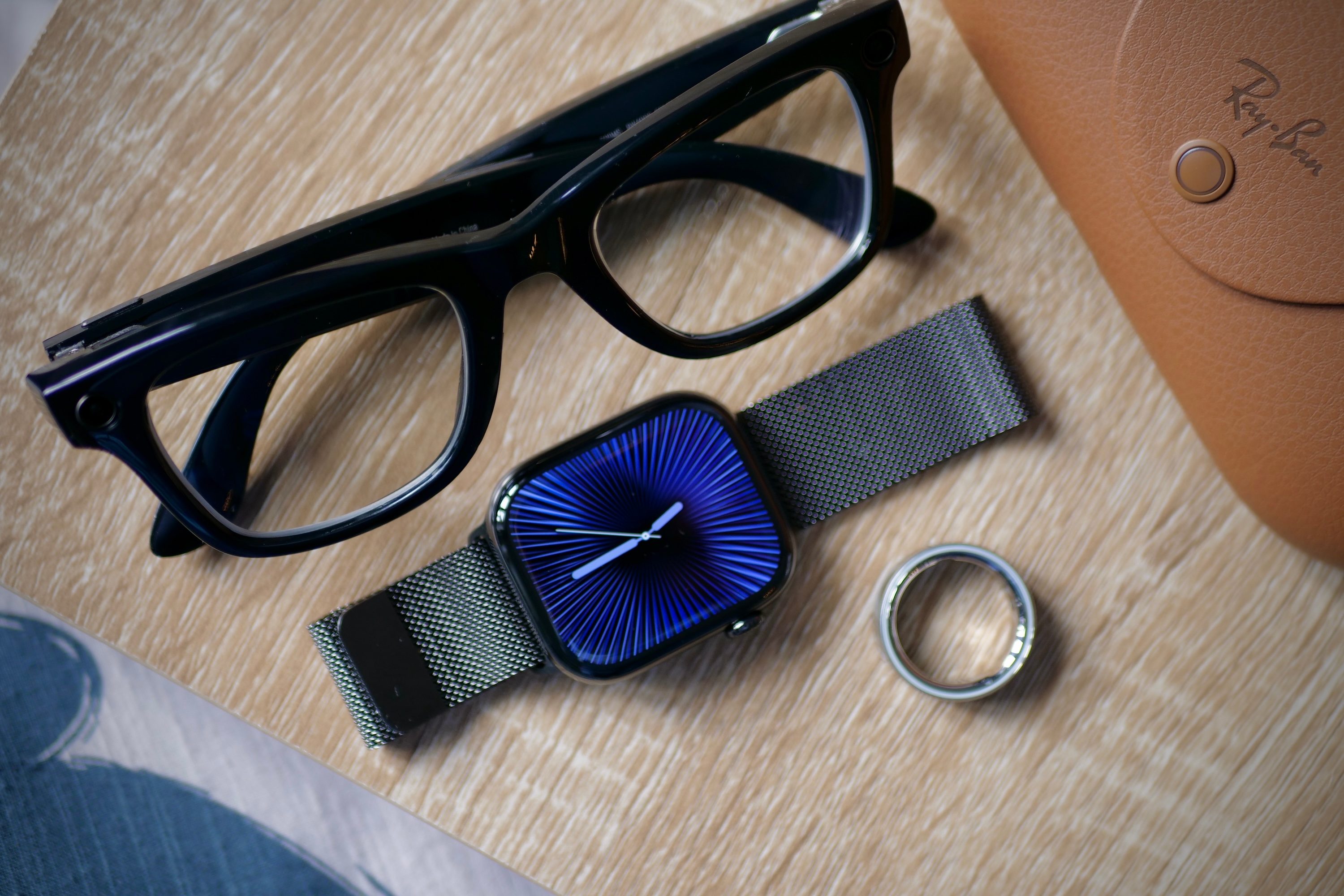 Les lunettes intelligentes Ray-Ban Meta, Apple Watch Series 10 et Oura Ring 4 sur une table.