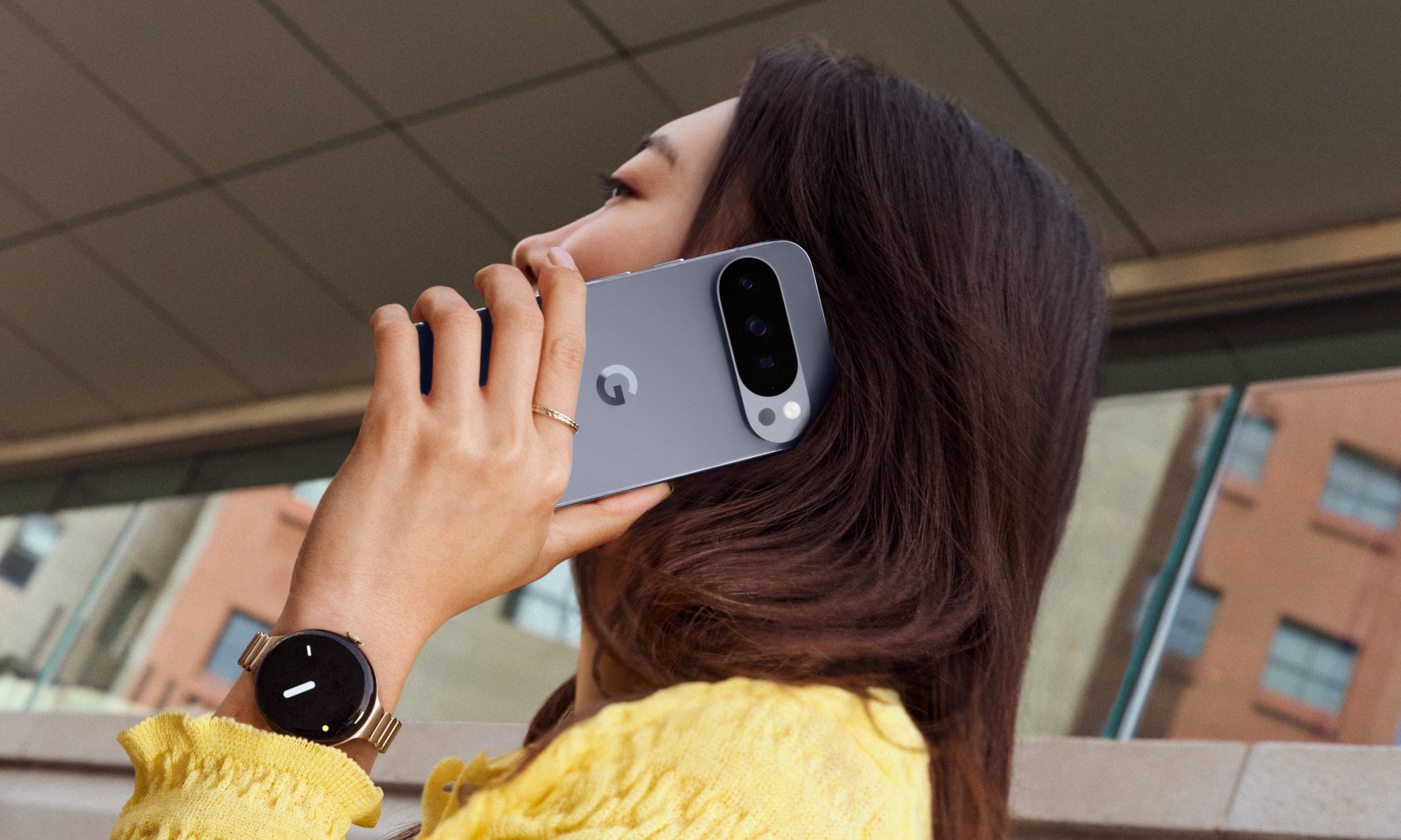 Une personne en haut jaune tenant le Pixel 10 Pro contre son oreille