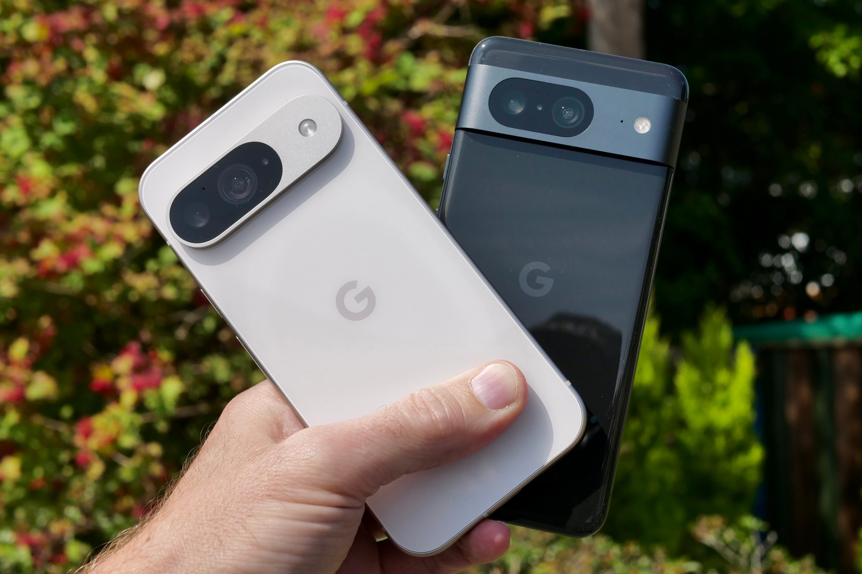 Une personne tenant le Google Pixel 9 et le Google Pixel 8.