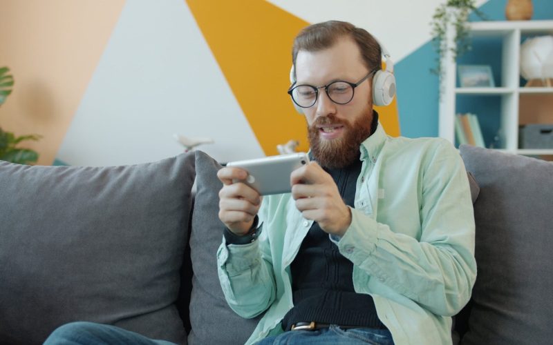 Man with headphones playing game on smartphone