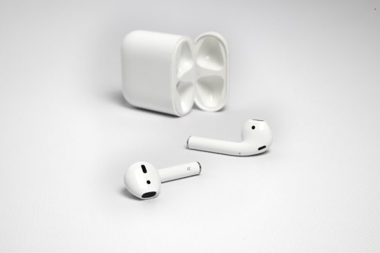 AirPods posés devant leur boîtier de charge ouvert
