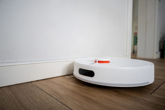 Aspirateur robot laveur nettoyant un parquet dans un salon