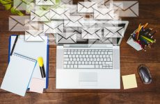 Ordinateur portable sur un bureau entouré d'enveloppes symbolisant des e-mails