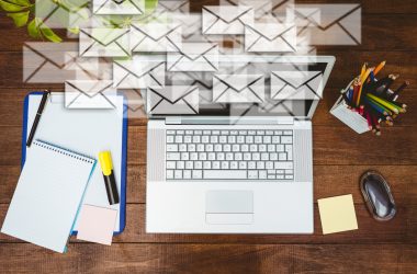 Ordinateur portable sur un bureau entouré d'enveloppes symbolisant des e-mails