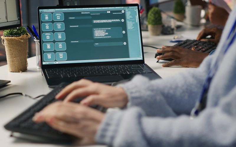 Ordinateur portable affichant la fenêtre de conversation d'un chatbot IA, devant une personne qui tape au clavier