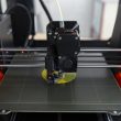 Buse d'une imprimante 3D FDM déposant du PLA jaune sur le plateau
