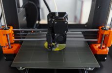 Buse d'une imprimante 3D FDM déposant du PLA jaune sur le plateau