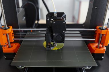 Buse d'une imprimante 3D FDM déposant du PLA jaune sur le plateau