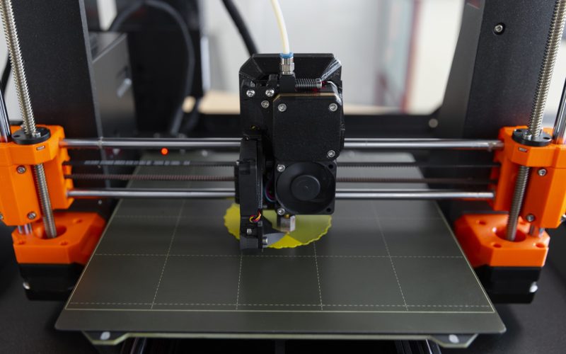 Buse d'une imprimante 3D FDM déposant du PLA jaune sur le plateau